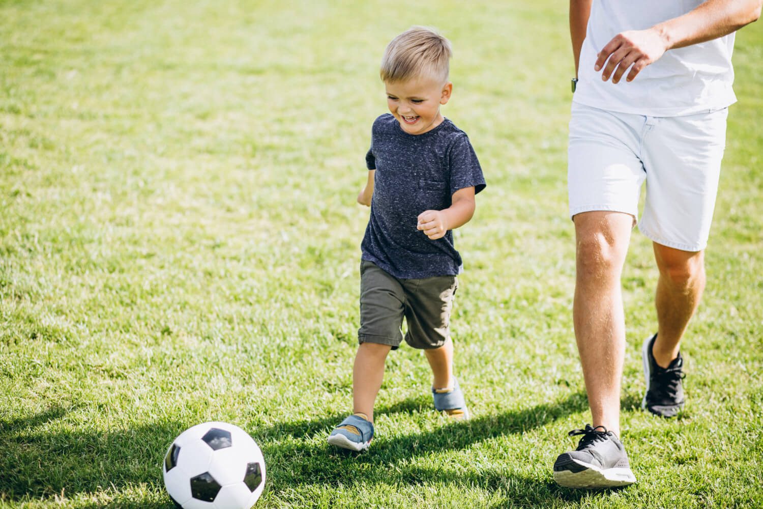father-with-son-playing-football-field